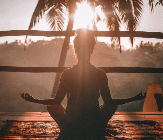 Frau meditiert bei Sonnenaufgang